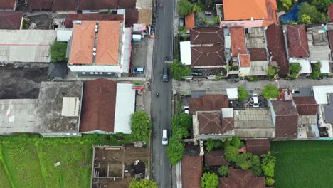 Antena-De-Arriba-Hacia-Abajo-De-Motos-Y-Coches-En-La-Carretera-Que-Pasa-Por-Los-Campos-De-Arroz-En-Bali,-Indonesia