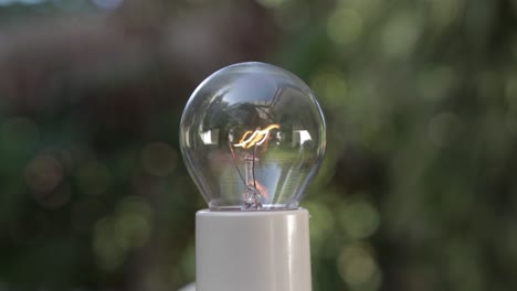 close-up on incandescent light bulb flickering from darkness to bright blurred background, 4k