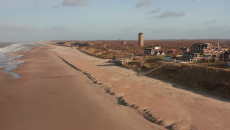 foto en órbita de una playa vacía con un pueblo turístico detrás de las dunas