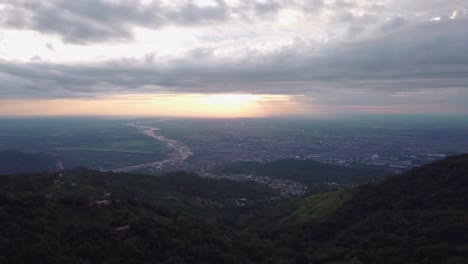 take aerial with drone, city in colombia dawning, great mountains with a colorful sky, orange sun.