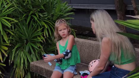 madre ayudando a su hija a ponerse un equipo de protección para patinar