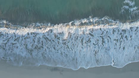 uae: aerial view of waves breaks on the beach, bird's eye view of ocean waves crashing and foaming against the empty shore, rough sea view