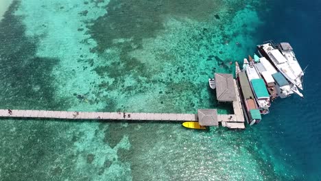 top view boats by wooden pier on paradise beach kanawa island, indonesia