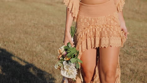 Elegante-Kaukasische-Frau,-Die-Ihr-Boho-Hippie-Kleid-Mit-Einem-Blumenstrauß-Winkt---Mittlere-Detailaufnahme