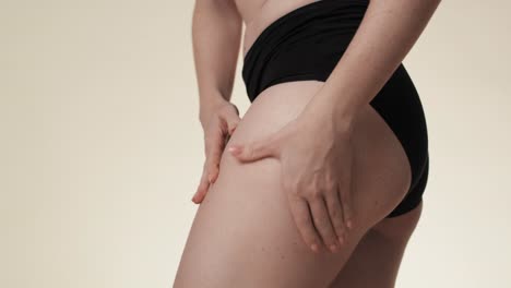 unrecognizable woman touching and pressing skin on her hip.