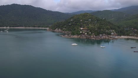 aerial view of a tropical beach with boats and a mountain in the background