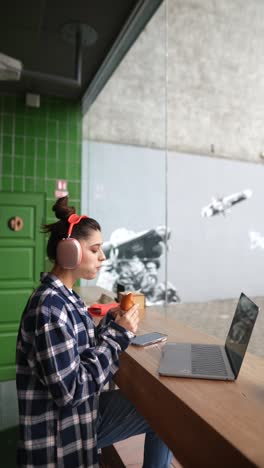 woman eating a croissant and working in a cafe