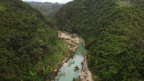 cinematic aerial shot moving down towards a blue river within a forest in cebu philippines, drone, asia