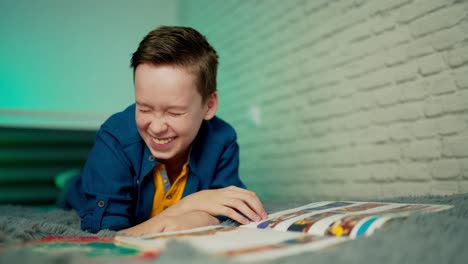 happy boy lying on bed reading book at home. home education.