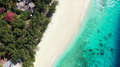 Idyllic-exotic-beach-with-white-sand-in-front-of-clear-calm-water-of-shallow-turquoise-lagoon-with-corals-and-rocks-on-seabed-of-coastline-in-Bali