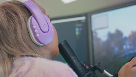 woman gaming at home sitting at desk wearing headphones for live stream