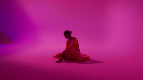 camera moves through studio equipment to show female kathak dancer wearing traditional indian dress preparing for performance 1