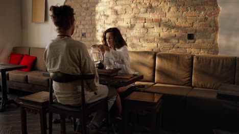 woman pouring tea in a cafe with a man