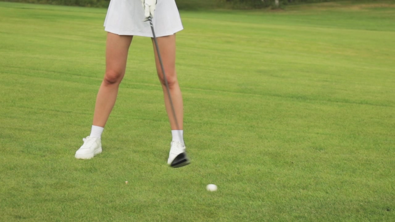 Golfista donna che colpisce una pallina da golf con un driver al rallentatore