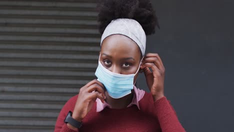 african american putting her face mask on in street