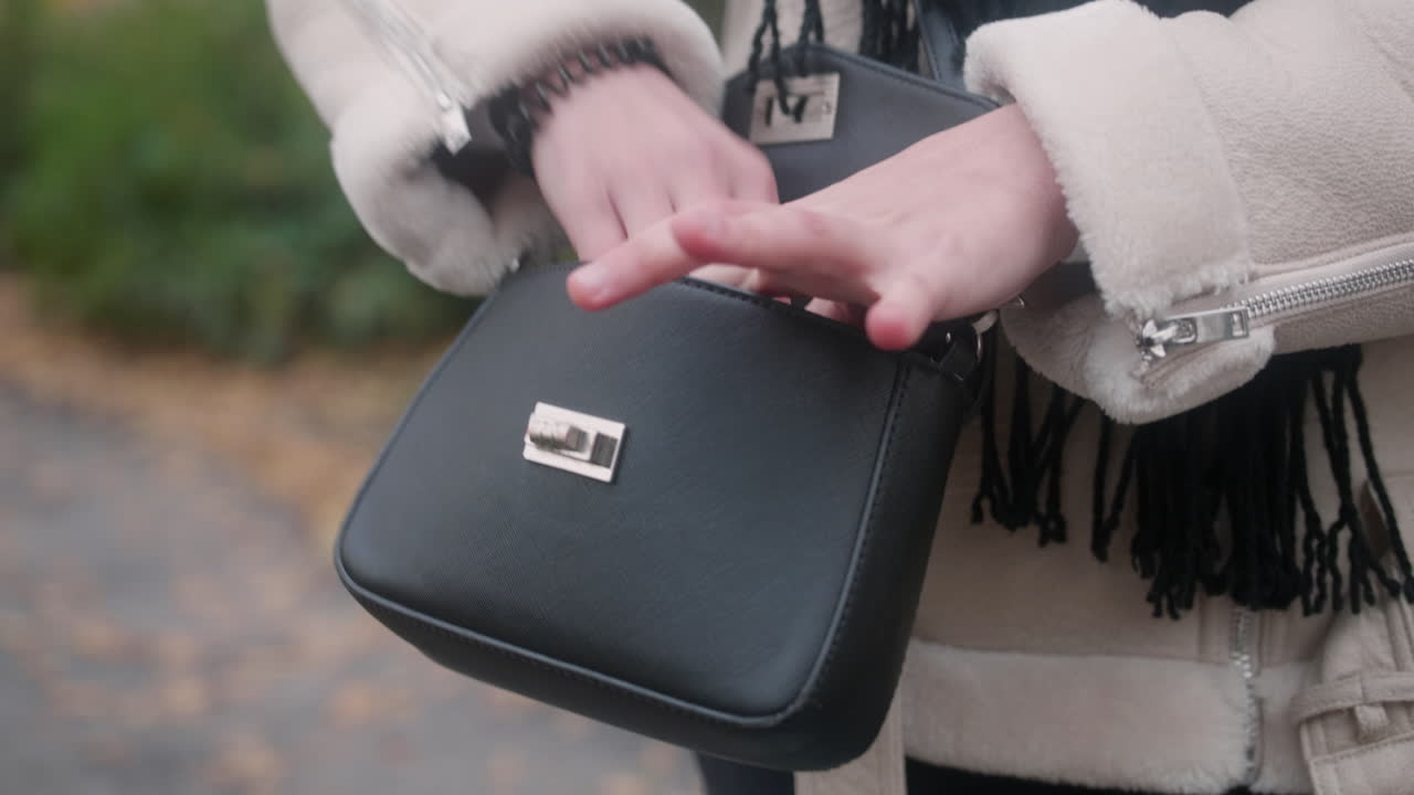 Primo piano di una borsa nera intorno alla vita di una donna che indossa un cappotto bianco caldo