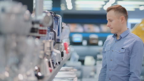 young handsome man in appliances store chooses blender for his cuisine