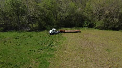 aerial abandoned cargo truck at the edge of a forest in a green field