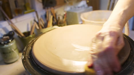 close up of male potter shaping clay for house sign on pottery turntable in ceramics studio