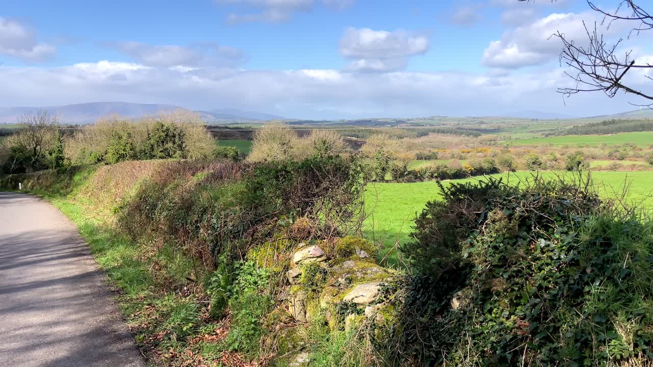 camino de campo en waterford, irlanda, a principios de la primavera, tierras de cultivo fértiles con el telón de fondo de las montañas comeragh.