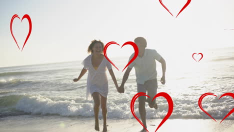 animation of red hearts over diverse couple in love holding hands running on beach in summer