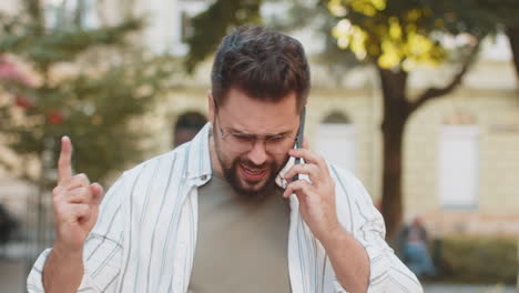 caucasian young man traveler arguing talking on smartphone while walking on urban city street