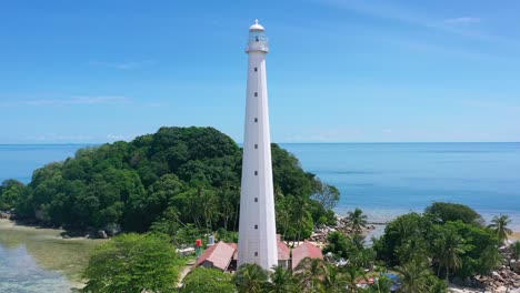 aerial of tourists on white sand beach with white lighthouse on lengkuas island