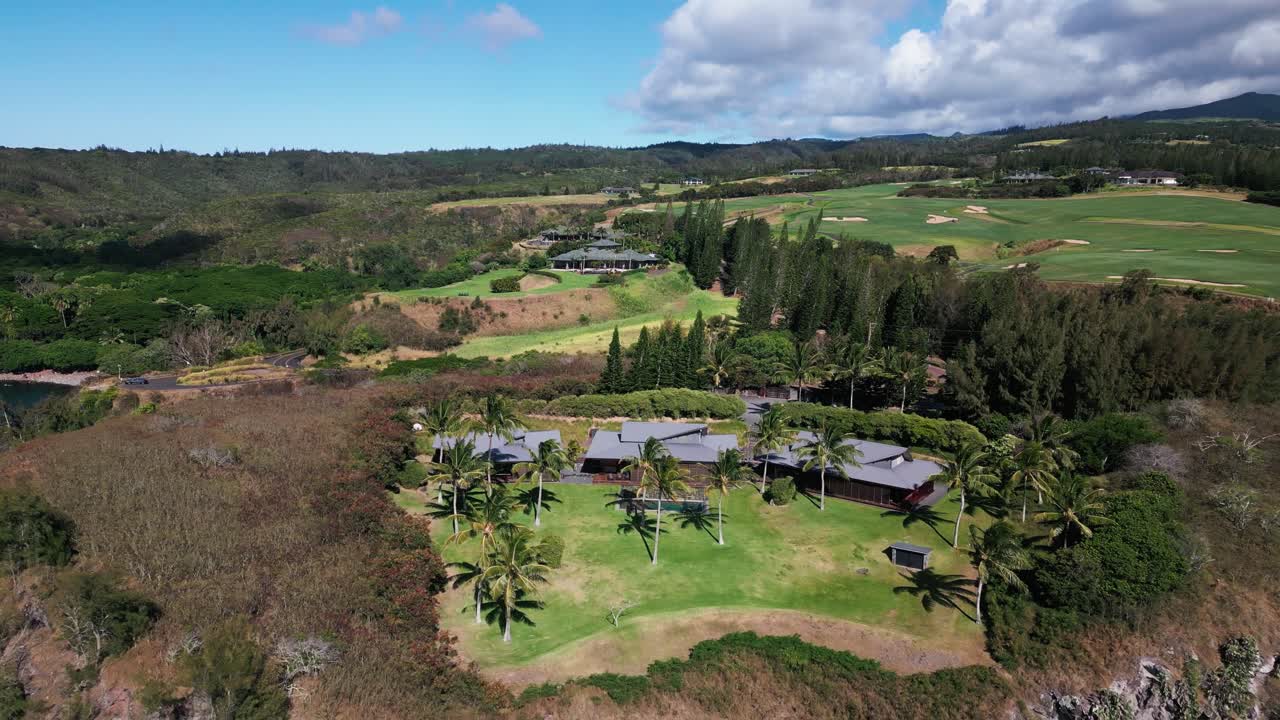 Drone reveals mansion on cliffside in tropical island with ocean bay and golf course