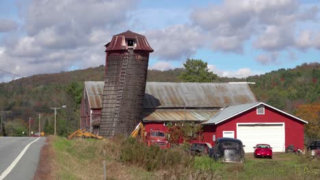 Coches-Viejos-Sentarse-Fuera-Junto-A-Un-Granero-Rojo-A-Lo-Largo-De-Una-Carretera-Rural-En-Vermont