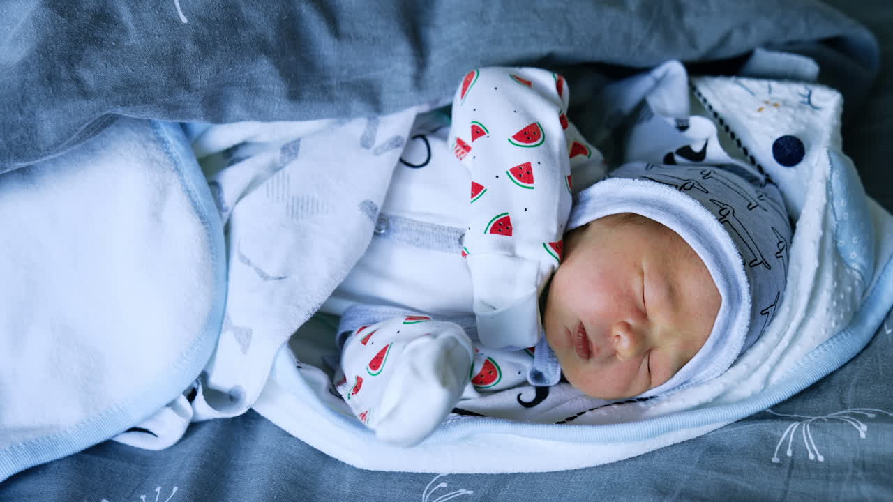 Lovely newborn Caucasian baby sleeping on the bed wrapped in blankets. Top view. Close up.