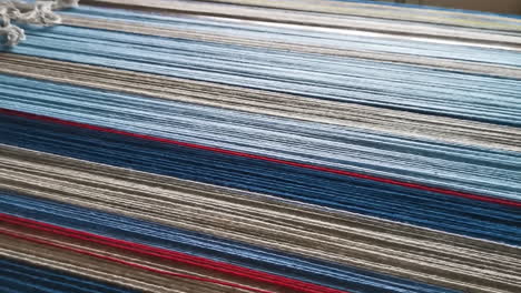 woven fibers or yarn for mat with shades of blue and red on table, detailed pan