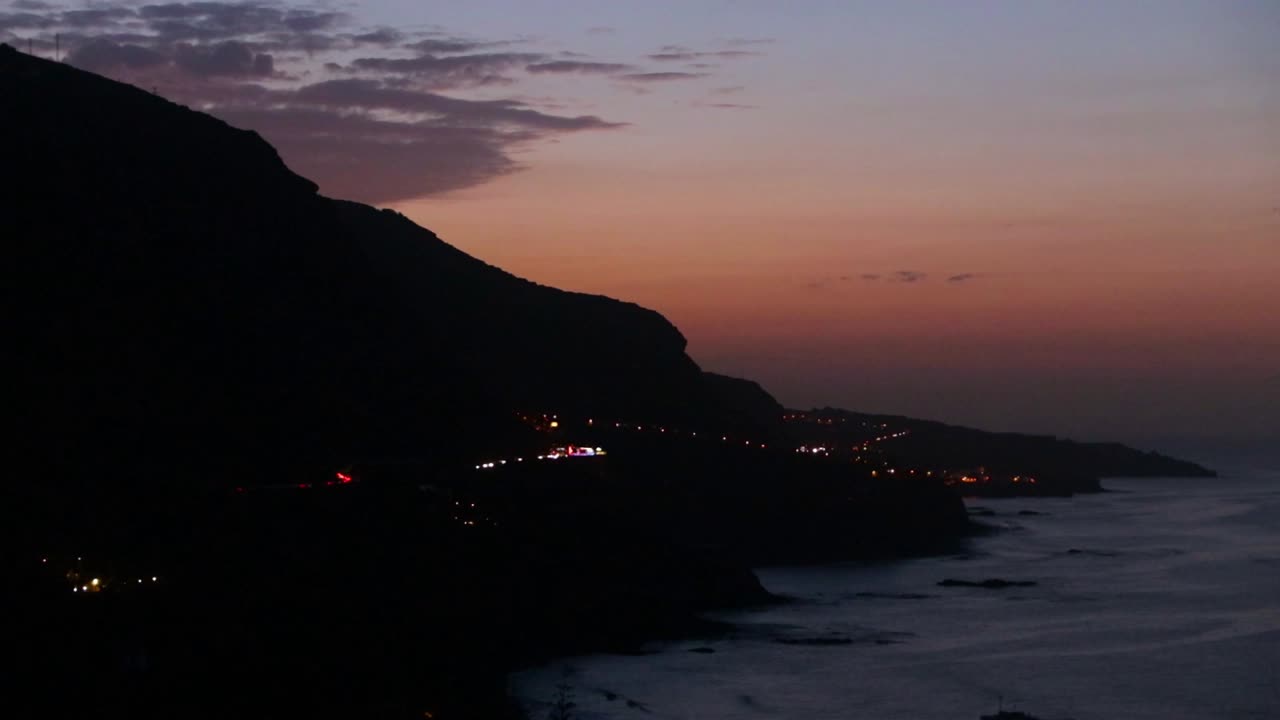 vista de un cielo dorado con montañas y una autopista en la distancia a lo largo de la costa, tenerife