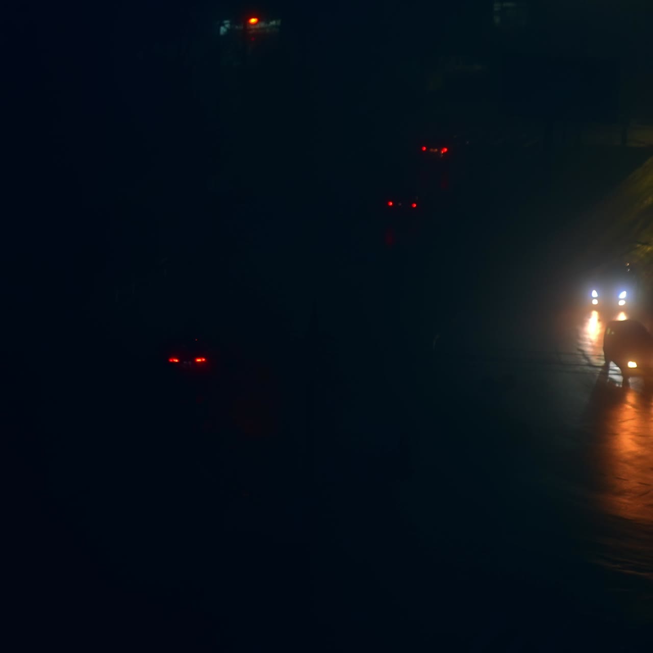 Slow traffic on the roads at nighttime. Private cars with lights on moving through the dark streets at blackout period