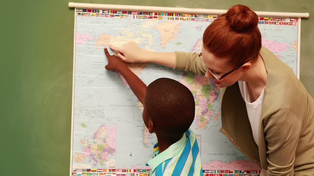 Cute pupil and teacher pointing to map