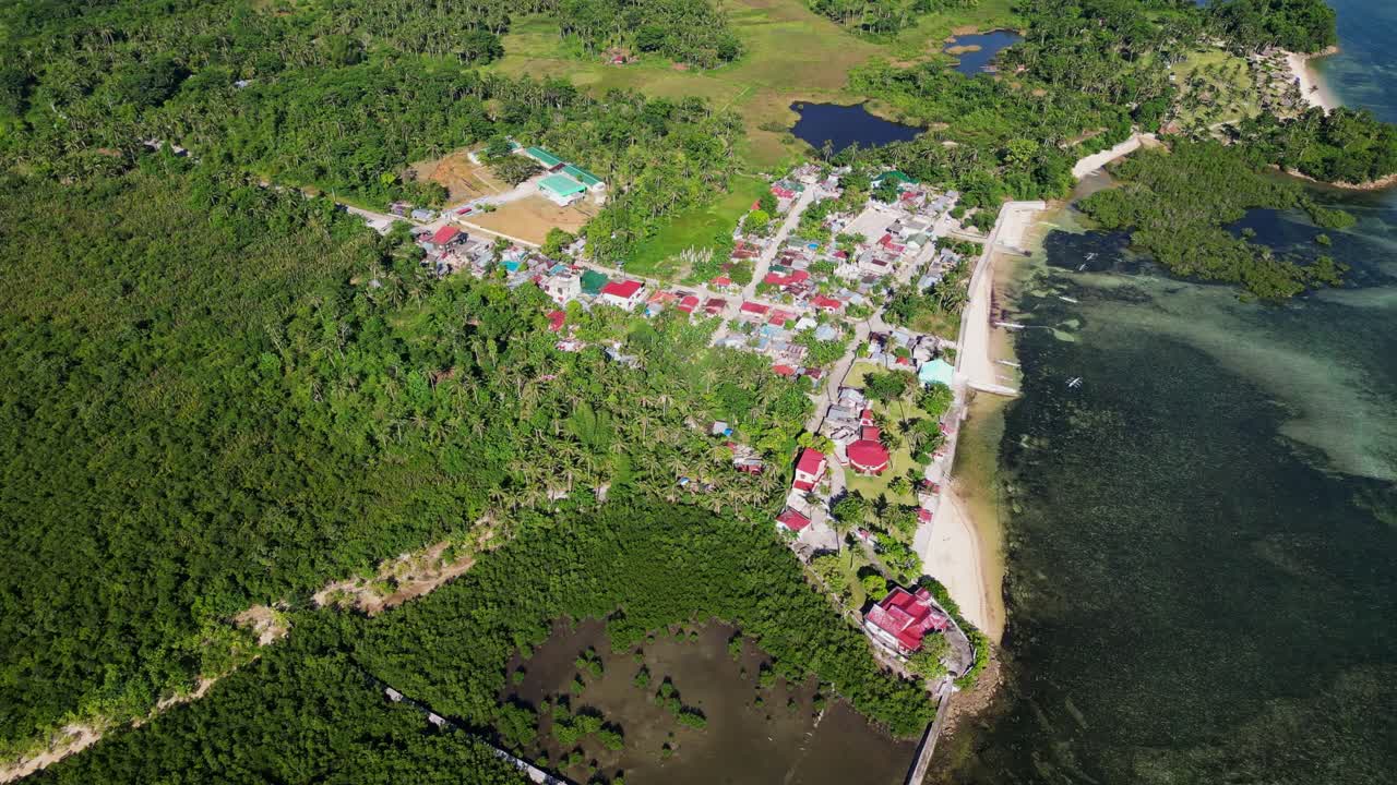 Scenic aerial overview of lush village town along tropical island coastline at Yocti, San Andres, Catanduanes, Philippines.