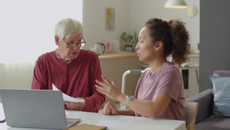 caregiver teaching senior man how to use laptop