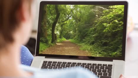 woman using laptop with pathway in forest 4k