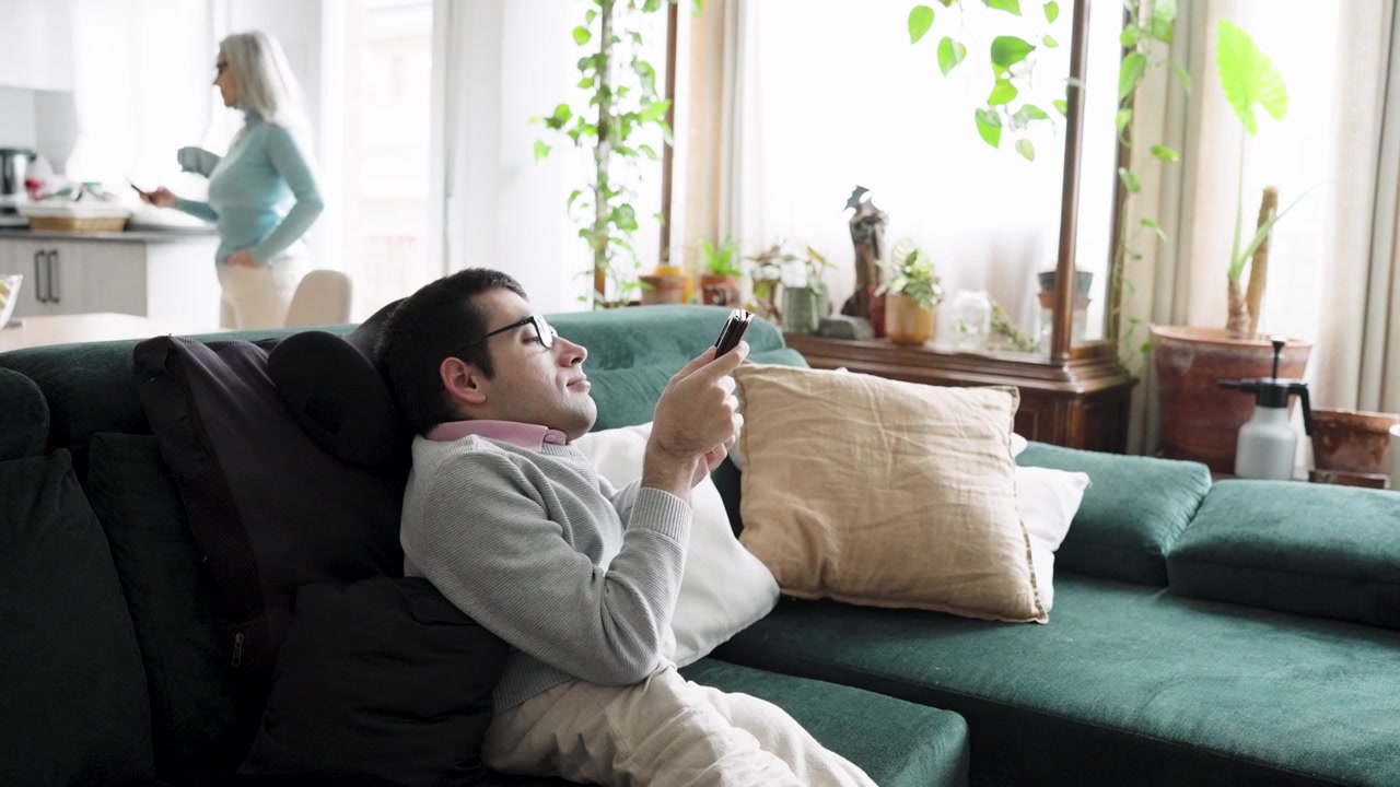 Giovane uomo che si rilassa sul divano usando lo smartphone a casa