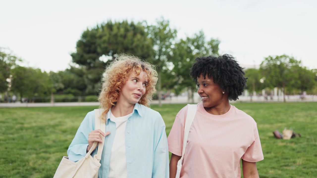 Twee diverse jonge vrouwen lopen en praten in een park