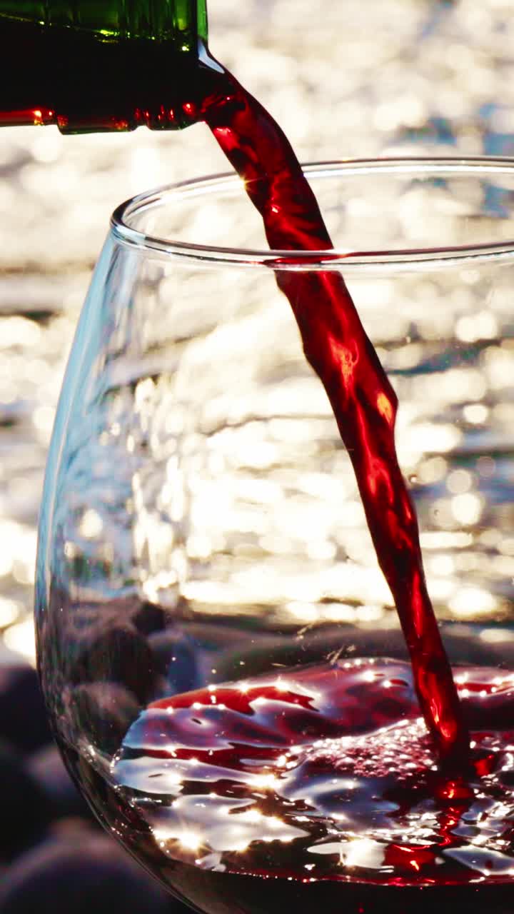 Vino tinto vertiéndose en un vaso con fondo de agua con gas