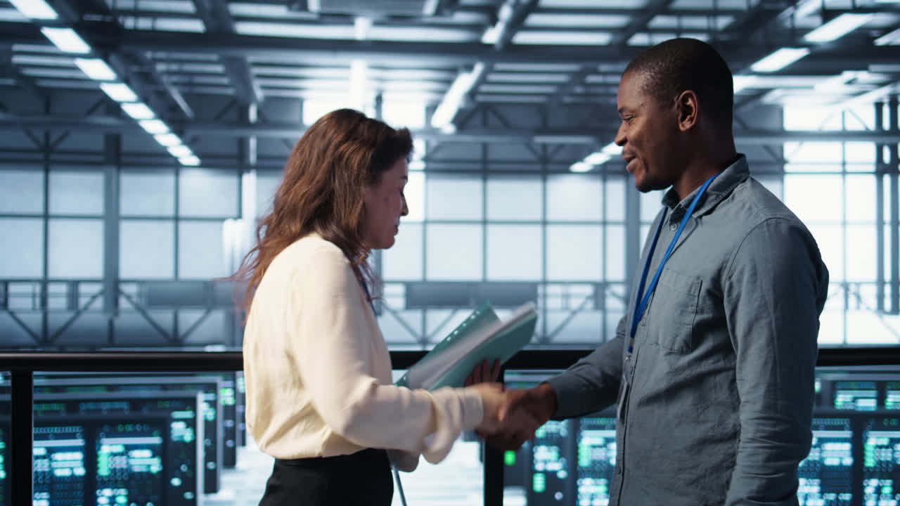 Cheerful admins meeting in data center to review reports, doing handshake