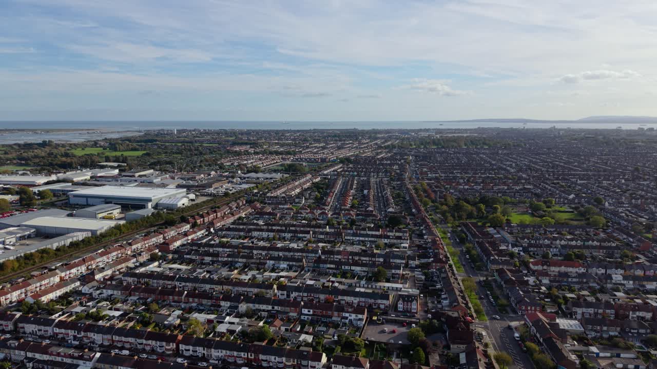 Volo esteso e lento di un drone su Portsmouth (Regno Unito) che rivela il variegato paesaggio urbano della città, con un'ampia area di case a schiera e vista sul mare e sul porto in una luminosa giornata di sole.
