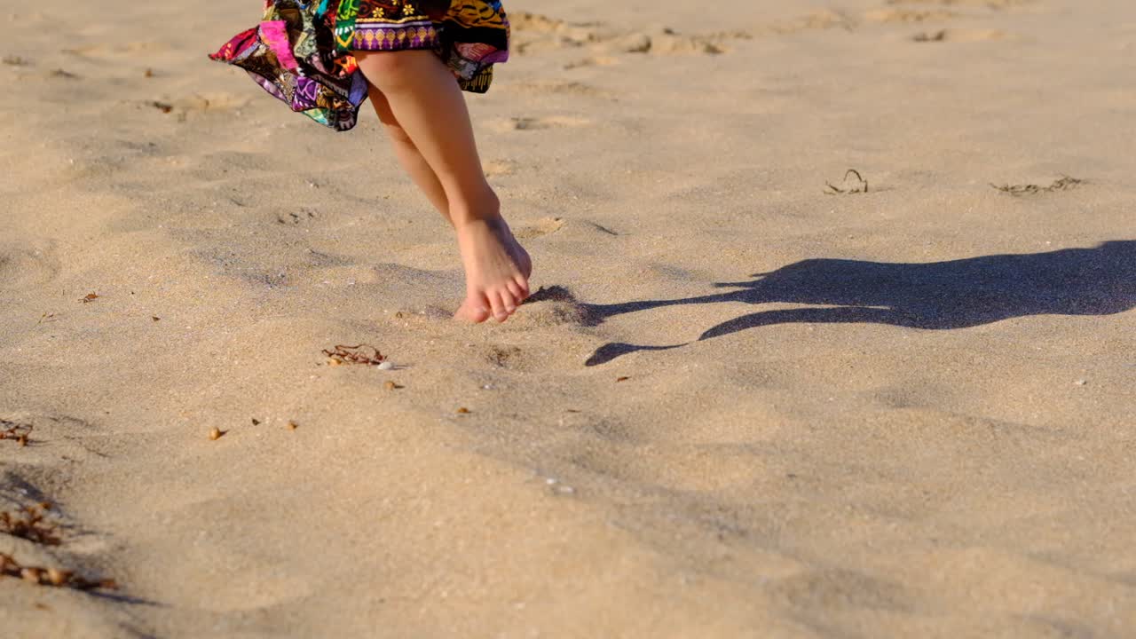 Young girl in a bright skirt running along beach