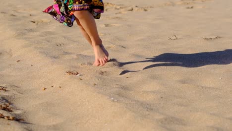 young girl in a bright skirt running along beach