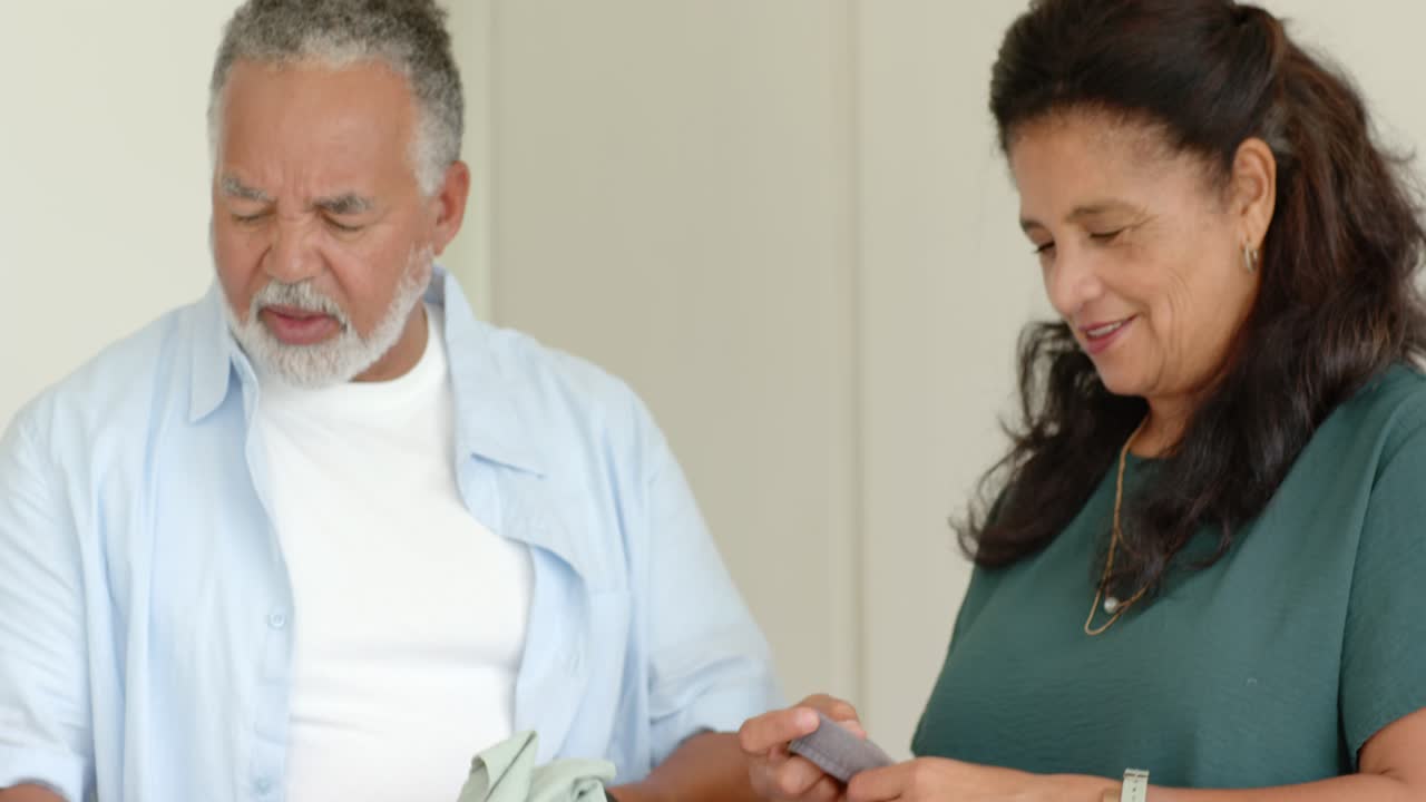 Casal idoso dobrando e embalando roupas em uma caixa de doação no quarto após ver a etiqueta de doação.