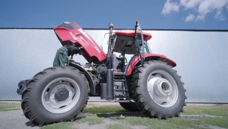 farmer mechanic repairing tractor. open tractor hood, engine. repair agricultural technology