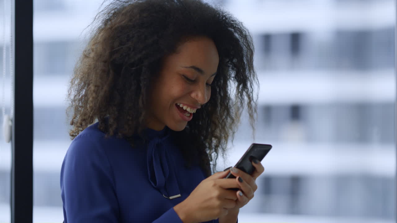 Excited african american woman celebrate good news work promotion on smartphone.