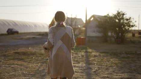 vista trasera de una mujer con una cesta que lleva verduras frescas o plantas recién recogidas