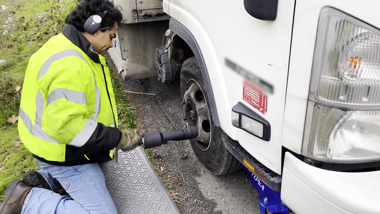 hombre latino cambiando el neumático de un remolque varado en la carretera