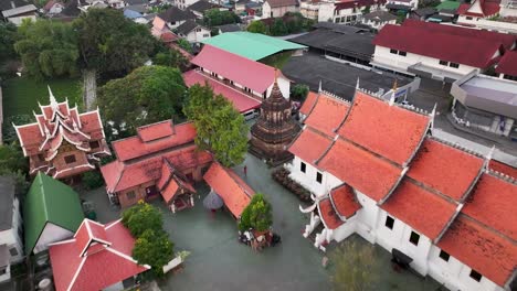 buddhist temple complex in city od chiang mai, thailand. drone reveal cityscape over buildings.